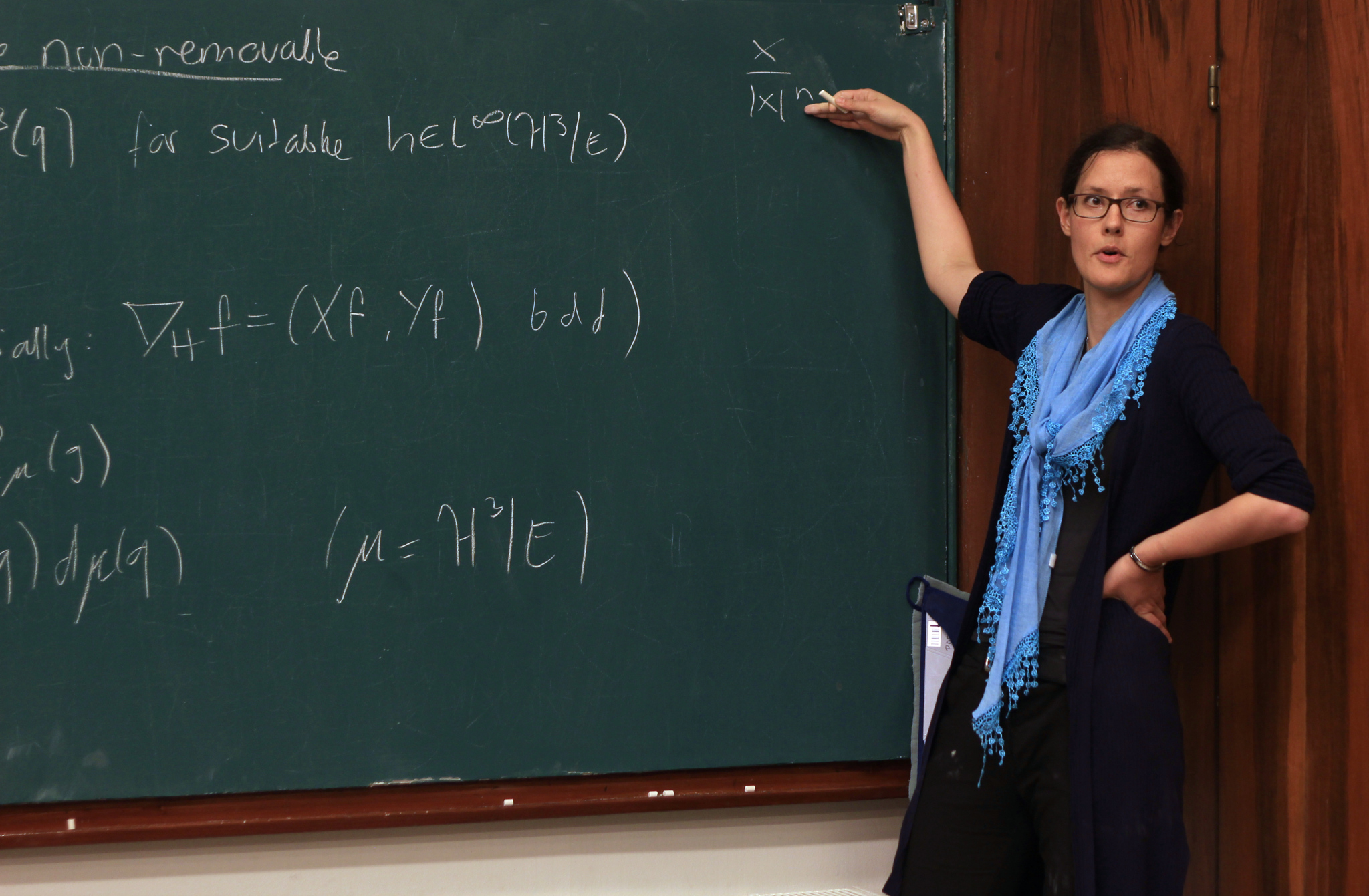 Female mathematician gives a blackboard lecture.